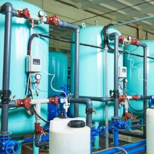 The interior of a water purification plant with an intricate filtration system and large blue storage tanks.