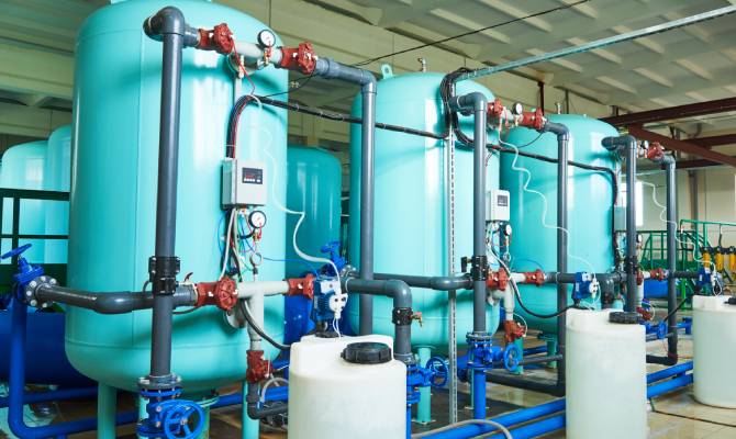 The interior of a water purification plant with an intricate filtration system and large blue storage tanks.