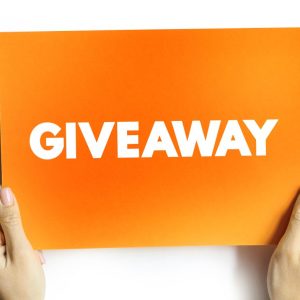A close-up of a person holding an orange card featuring the word "giveaway" in bold, eye-catching typography.