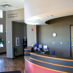 A hospital lobby with a hallway leading toward gastroenterology and the endoscopy center, with a reception desk.