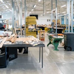 Interior of a small industrial warehouse with a large table covered with material and other equipment in the background.