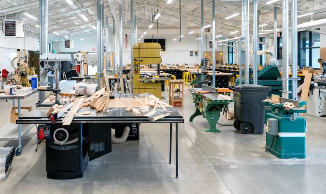 Interior of a small industrial warehouse with a large table covered with material and other equipment in the background.