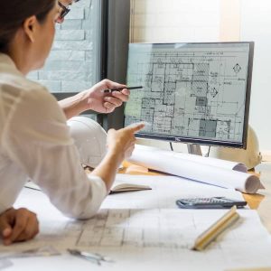 A professional architect designer team working and looking at a computer, discussing a building plan design project.