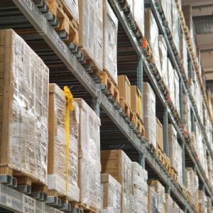 An upward angle of a pallet racking system in a warehouse. Five tiers are visible, each lined with wrapped and loaded pallets.