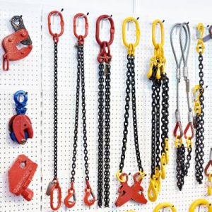 An angled image of various different lifting and rigging tools and equipment hanging against a white wall.