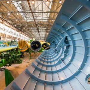 A view of the inside of a half-completed helicopter hull part in an aviation manufacturing factory.