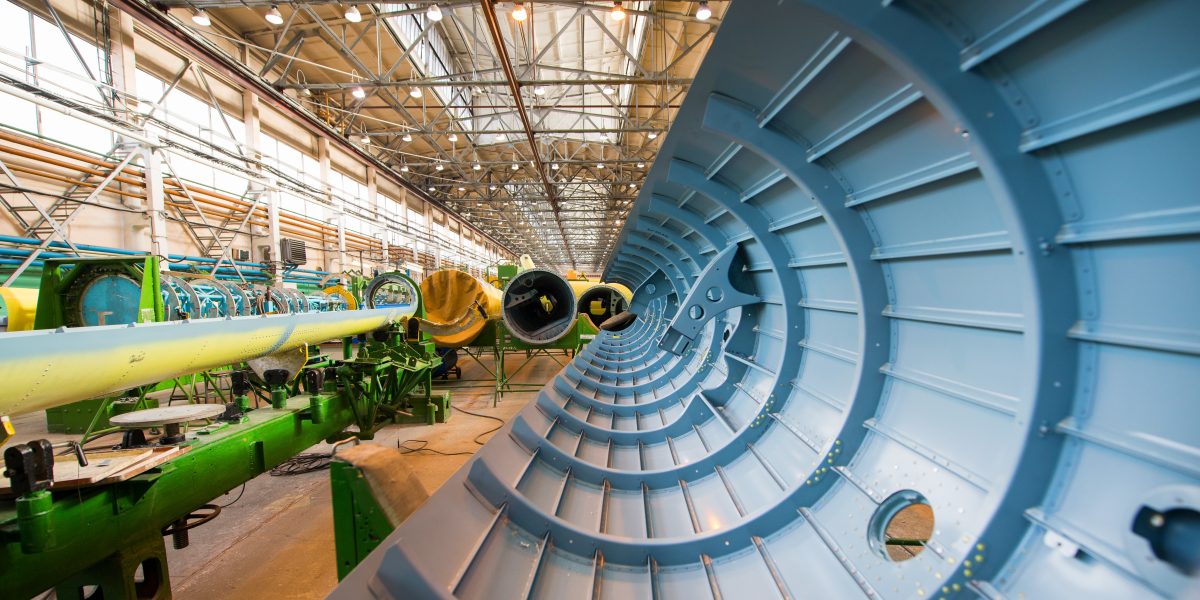 A view of the inside of a half-completed helicopter hull part in an aviation manufacturing factory.
