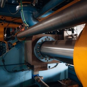 A yellow and blue hydraulic component contains several black wires. The silver hydraulic is sitting still.