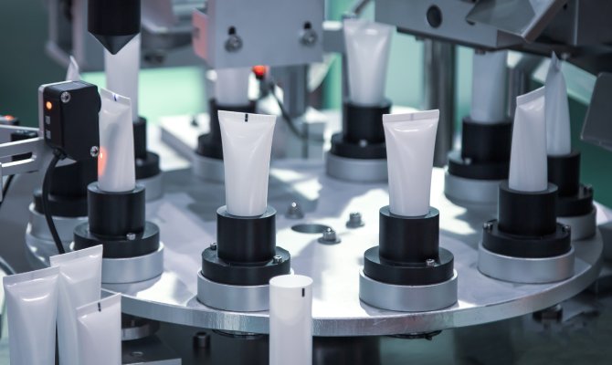 An automatic circular machine holds several blank plastic tubes. More tubes are ready to be implemented in the process.
