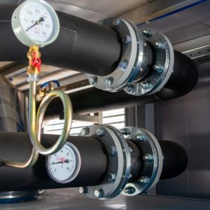 An industrial piping system showcasing multiple pipes being connected together by a metal expansion joint.