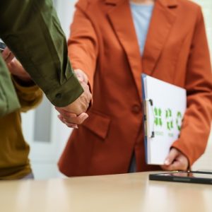 Two business professionals shaking hands after agreeing to a waste contingency plan. One person has a clipboard.