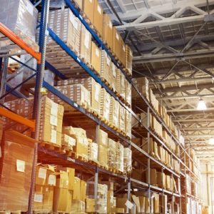 The inside of a warehouse with a long hallway lined with shelving units that hold products for the facility.
