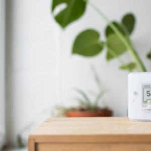 A close-up of a CO2 indoor air quality portable machine on a light wooden table in someone's living room.