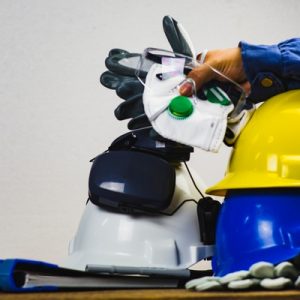 A collection of PPE with two hard hats stacked on top of one another. There are also safety glasses and work gloves.