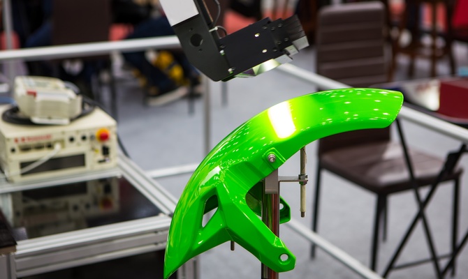 A lime green part is attached to a mount. A robotic arm hovers over the part collection data points.