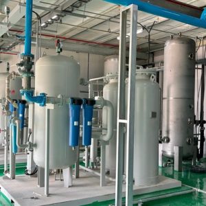 Large compressed air tanks and bright blue piping fill an industrial facility with a green floor and metal ceiling.